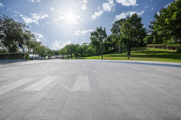 Empty square floor with green trees and blue sky sun background in the park.