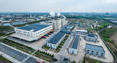 Aerial view of modern factory buildings with solar panels and trucks at logistics center.