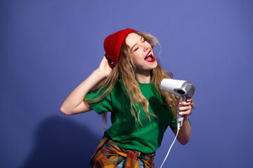 Young woman sings into a style microphone wearing green shirt red beanie in a studio with vibrant...