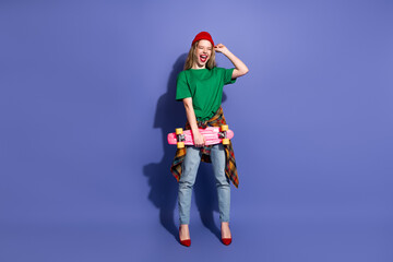 Young girl with skateboard wearing green shirt red beanie and plaid shirt tied at waist against...