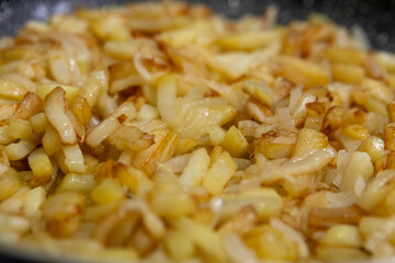 Sliced potatoes with onions are deliciously fried in a frying pan.