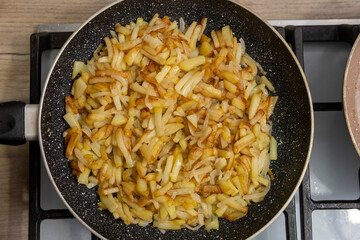 Sliced potatoes with onions are deliciously fried in a frying pan.