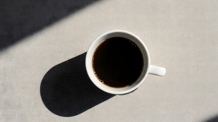 Top View of a White Coffee Mug Filled with Black Coffee on a Neutral Textured Surface, Featuring Dramatic Shadow and Sunlight, Perfect for Minimalism and Morning Concepts