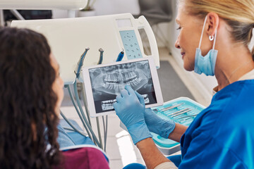 Dentist and patient watching x-ray on digital tablet