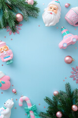 Minimalist vertical frame of pastel Christmas toys and confetti on a light blue background.
