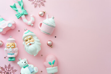 Sweet pastel pink Christmas ornaments flat lay with nutcracker, Santa, and teddy bear.