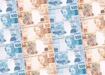 Background texture of Brazilian money banknotes, 100 and 50 reais notes, background for video or scenery. Concept of award or payment, fortune.