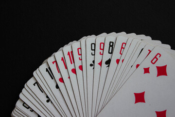 Macro view of fanned playing cards showing numbers and suits. Textured paper edges visible for a realistic look.