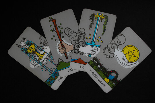 Set of four tarot aces cups, wands, swords, pentacles fanned on a black background. Colorful occult symbolism