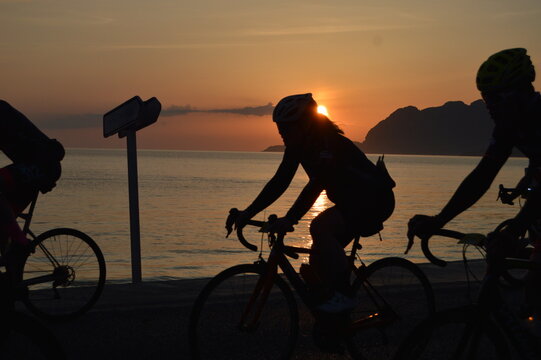 silhouette of a couple of bikes on the beach at sunsrise with orange sun.