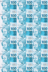 Background texture of Brazilian money bills, 100 reais notes, background for video or scenery. Concept of award or payment, fortune.