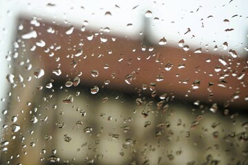 Abstraktes Motiv mit Regentropfenmuster vor alter braun-beiger Fachwerkscheune mit rotem Ziegeldach und Schornstein vor weißem Himmel in Dorf bei Sturm und Regen am Morgen im Herbst