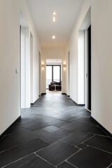 Modern hallway with matte black slate flooring and contrasting white walls, geometric composition