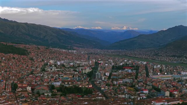Cusco Cuzco Peru Per&uacute; cityscape international airport aerial drone high altitude snow capped Peruvian Andes colorful Inca neighborhood buildings sunset golden hour blue skies clouds circle left motion