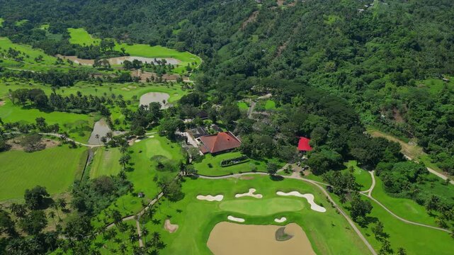 A slow push aerial highlighting the expansive grounds of Canlubang Golf and Country Club, revealing manicured fairways, water puddles, and tropical greenery in Calamba Laguna, Philippines