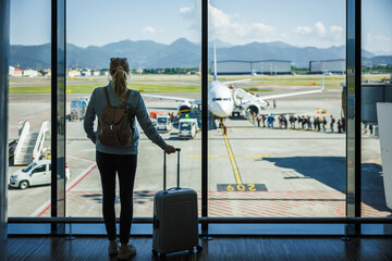 Woman passenger travel with carry-on luggage waiting in airport terminal before boarding to airplane. Solo traveler on her holiday trip © encierro