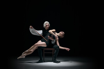 Classical conductor shaping dancer body like a musical instrument on dark stage. Concept of human form as tuned instrument, precise correction, expressive silence, and elevated art culture.