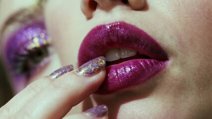 Close-up of a person applying glittery purple lipstick with matching nail polish and eye makeup