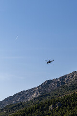 A helicopter flies against the backdrop of mountains. Makarska, Croatia.