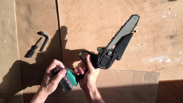 Hands connect battery to mini chainsaw. Concept for DIY, woodworking, and home improvement projects. Good for blogs, tutorials, or product demonstrations.