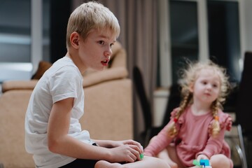 A 9-year-old boy with hearing aids plays naturally with his 4-year-old sister. Authentic sibling...