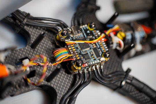 detailed close up of fpv drone electronic components on carbon fiber frame, neutral background, clear negative space, clean composition, balanced framing, minimalist layout, editorial friendly