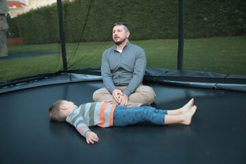 Father and son relaxing on backyard trampoline