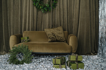Velvet sofa with gifts and green wreath on sparkly floor indoors