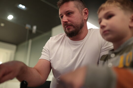 Father guiding son while learning or playing indoors - Powered by Adobe