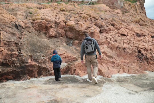 Father and son walking along rocky coastline exploring nature