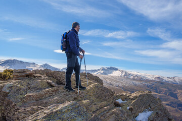 Hiker standing on rocky mountain summit admiring sierra nevada