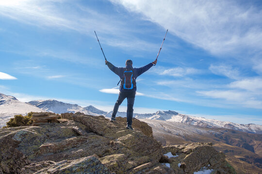 Hiker celebrating success standing on mountain peak in sierra nevada