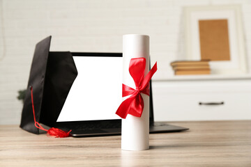 Diploma, graduation cap and laptop on wooden table indoors, closeup