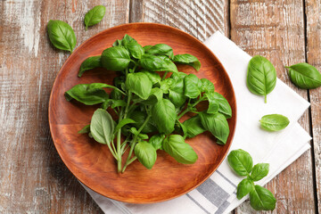 Fresh basil leaves and napkin on color wooden table, flat lay