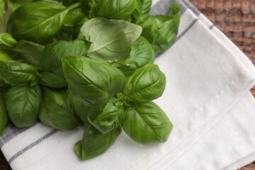 Fresh basil leaves and napkin on wooden table, top view