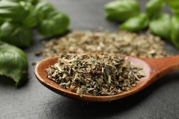 Fresh and dry basil leaves on black table, closeup