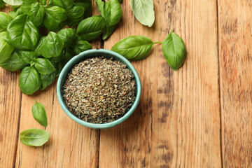 Dry basil in bowl and fresh green leaves on wooden table, flat lay. Space for text