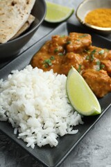 Chicken tikka masala with rice served on grey textured table, closeup