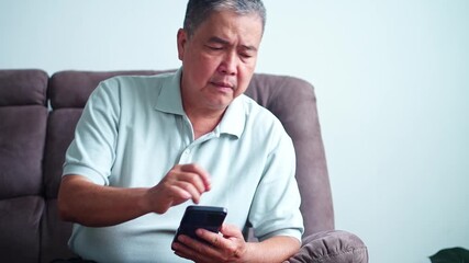 Concerned elderly asian man reviews documents and checks phone for important information - Powered by Adobe