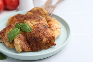 Tasty roasted chicken thighs with basil served on white tiled table, closeup. Space for text