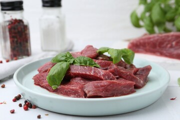 Pieces of raw beef meat and spices on white table, closeup