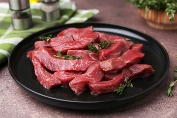 Pieces of raw beef meat and spices on brown table, closeup