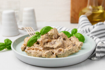 Tasty beef Stroganoff with basil on white table, closeup
