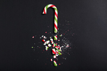 Crushed candy cane on black background, flat lay. Christmas treat