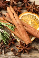 Different spices, fresh rosemary and dry orange slices for mulled wine on wooden table, flat lay