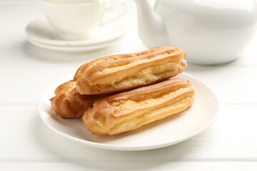 Fresh tasty eclairs on white wooden table, closeup