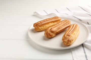 Fresh tasty eclairs on white wooden table, closeup. Space for text