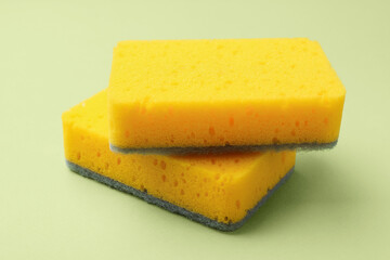 Kitchen sponges on light green background, closeup