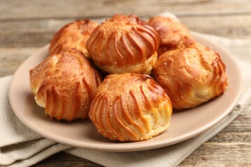 Tasty profiteroles on wooden table, closeup. Delicious dessert