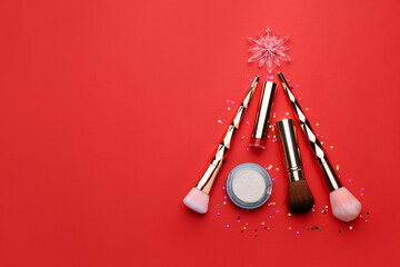 Christmas tree made with makeup products and brushes on red background, flat lay. Space for text